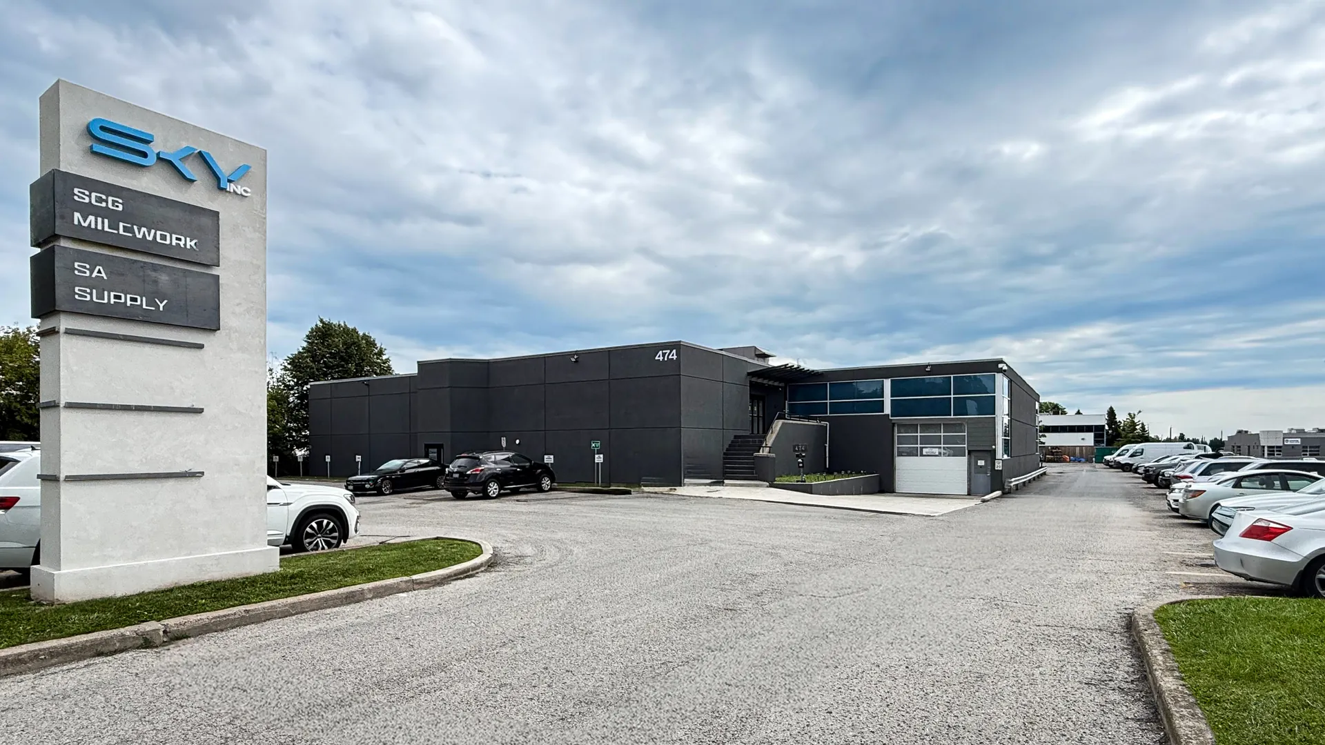 The Sky Group head office at 474 Iroquois Shore Rd., Oakville — a dark grey two-storey building behind the SKY Inc, SCG Millwork and SA Supply pylon sign