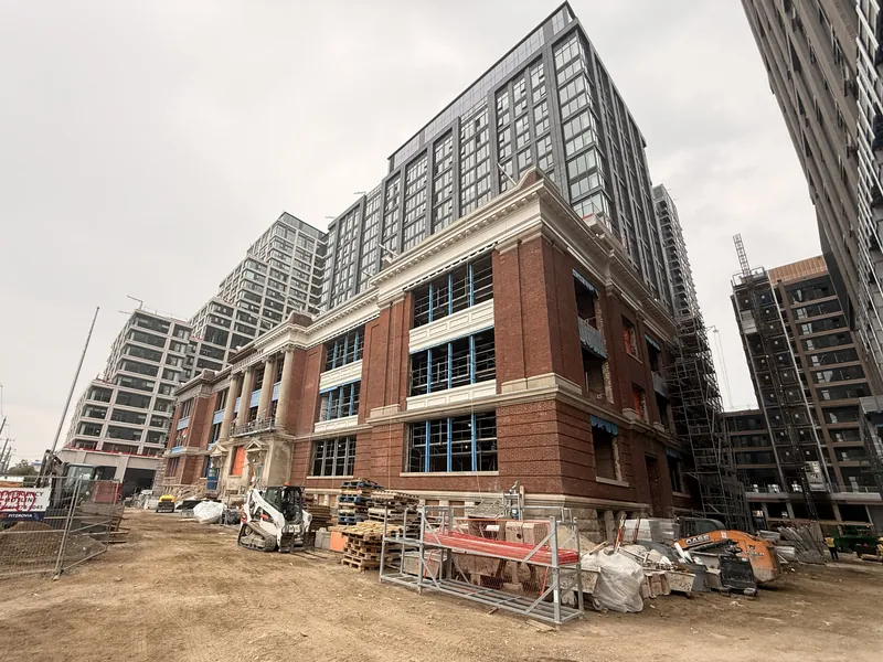 Heritage red-brick facade under restoration, scaffolded, among new residential towers