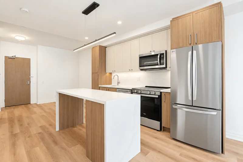 Suite kitchen with wood-grain cabinetry and a waterfall quartz island — 61 Yorkville Ave, Toronto