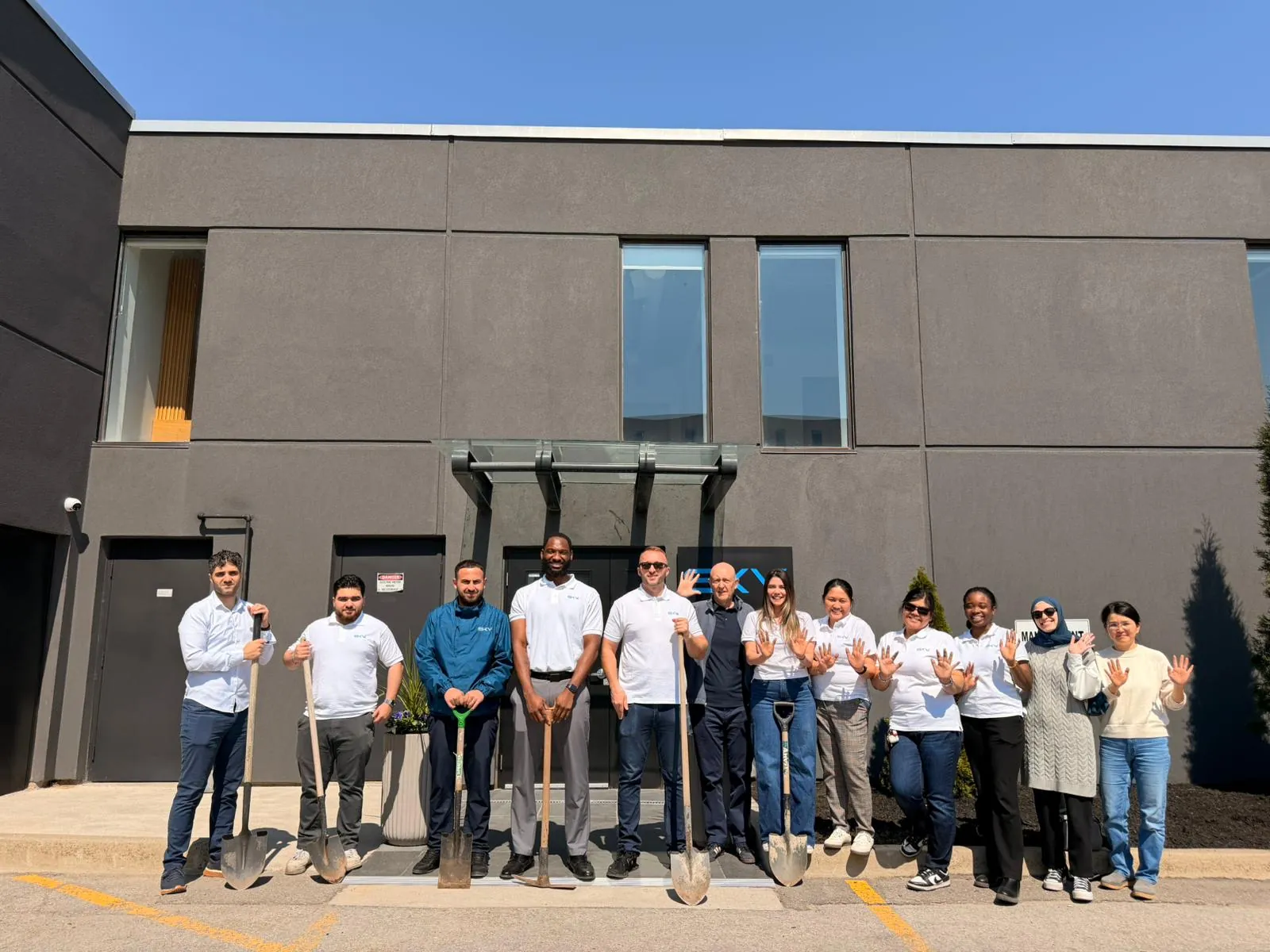 Sky Group team members holding shovels outside the Oakville head office on Earth Day