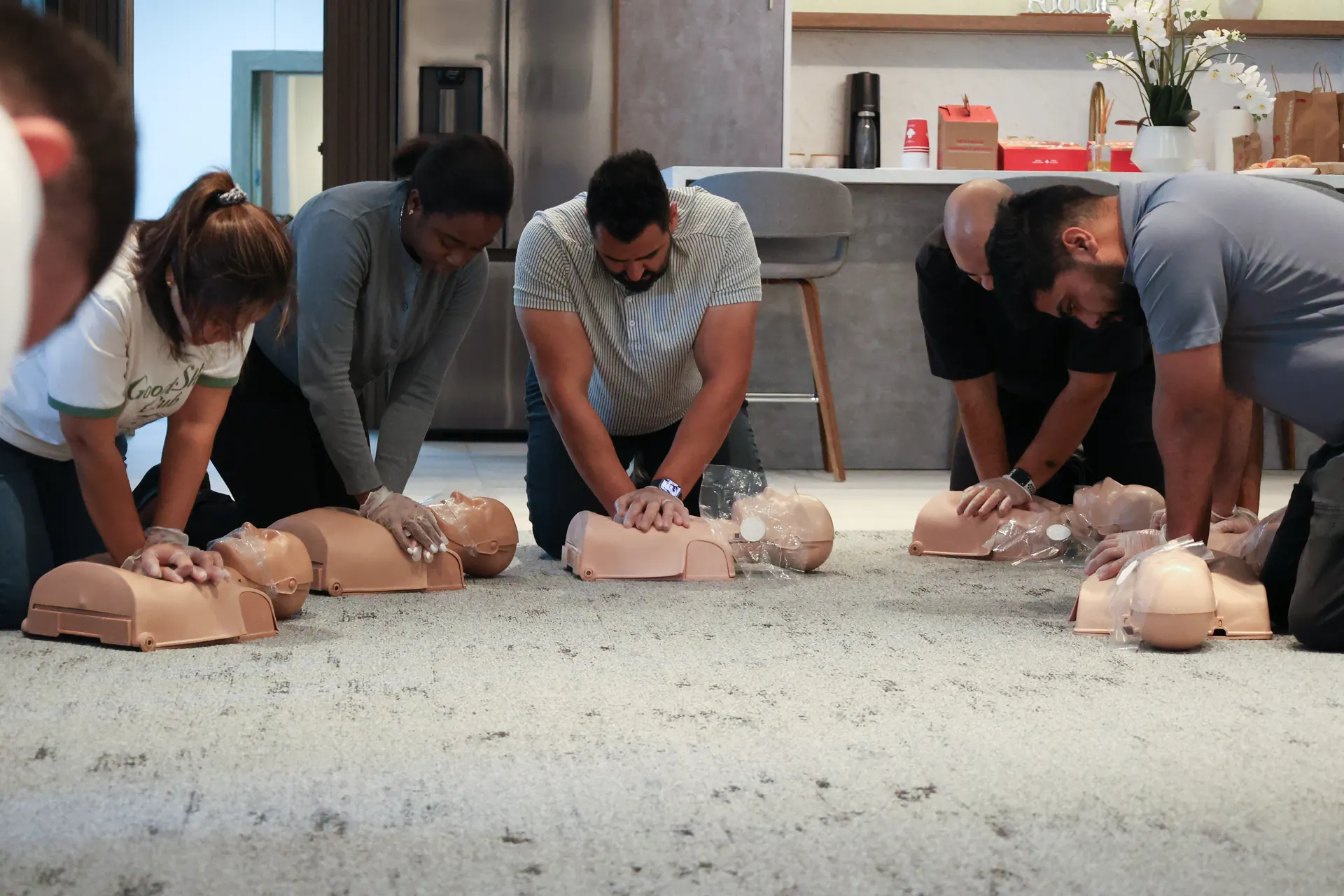 Team members kneeling on the floor practising chest compressions on CPR training manikins