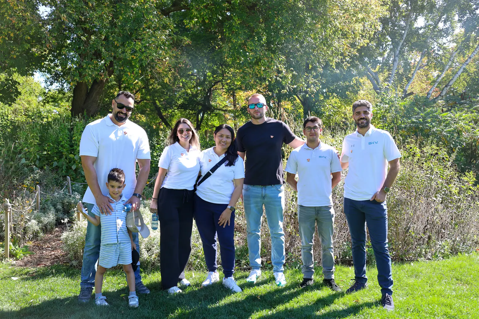 Sky Group team members standing together in a sunlit garden