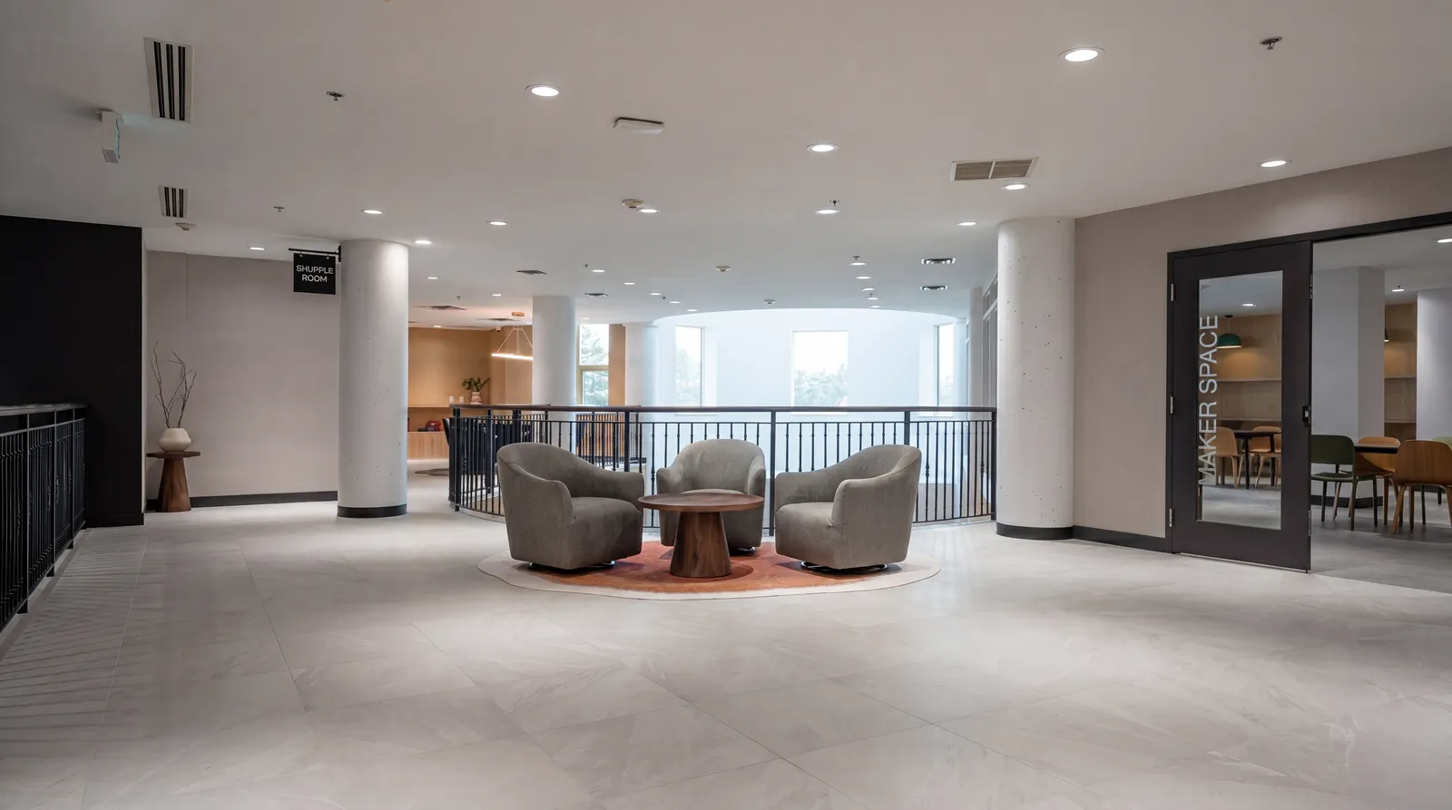 Mezzanine lounge overlooking the atrium, with swivel armchairs around a round wood table
