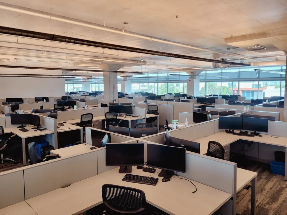 Open-plan office floor with rows of dual-monitor workstations
